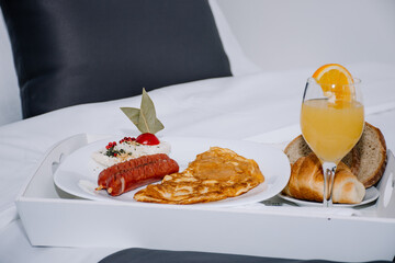 appetizing combination of sausages and an omelette with a glass of orange juice and bread served on...
