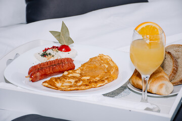 appetizing combination of sausages and an omelette with a glass of orange juice and bread