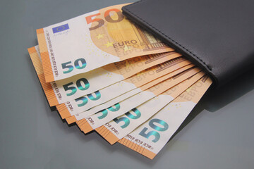 Fifty euro bills, various banknotes inside a wallet, close-up on dark background. Cash money