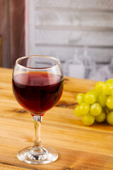 Glass of red wine and grapes on a wooden background. Shallow depth of field. Blurred background