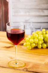 Glass of red wine and grapes on a wooden background. Shallow depth of field. Blurred background