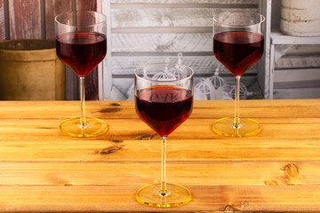 Three glasses of red wine on a wooden background. Shallow depth of field. Blurred background