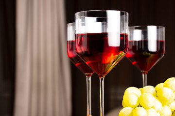 Three glasses of red wine and grapes on a dark background. Shallow depth of field. Blurred background