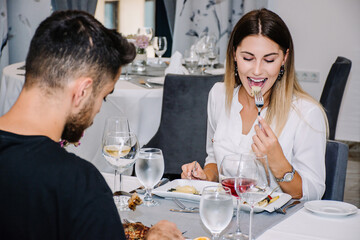woman excited about the food she is eating on a date in a restaurant with her partner