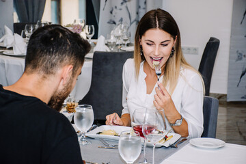 woman excited about the food she is eating on a date in a restaurant with her partner