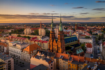 Aerial drone view of the Cathedral of St. Peter and Paul the Apostles and old town buildings before sunset. The sun's rays beautifully highlight the urban architecture in Legnica, Poland - obrazy, fototapety, plakaty