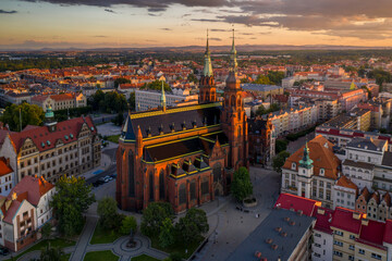 Fototapeta na wymiar Aerial drone view of the Cathedral of St. Peter and Paul the Apostles and old town buildings before sunset. The sun's rays beautifully highlight the urban architecture in Legnica, Poland