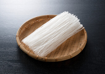 glass noodles in a colander on a black background