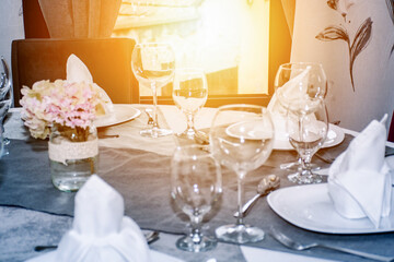 table decorated with plates, cutlery for every person and glasses while there is a bright sunny day outside