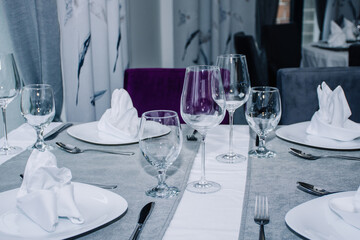 a table for two decorated with glasses for wine, cutlery and dishes with napkins