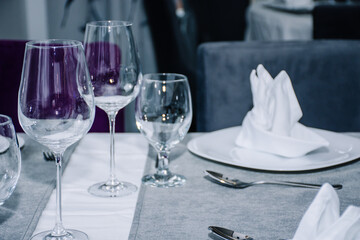 table decorated with cutlery and  glasses for dinner inside a beautiful restaurant