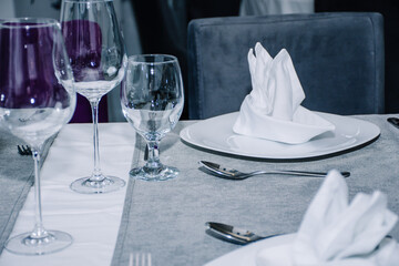 table decorated with cutlery and  glasses for dinner inside a beautiful restaurant
