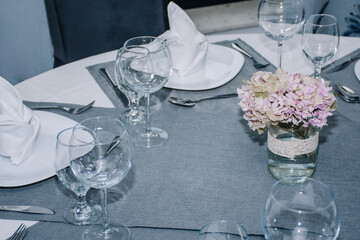 table decorated with cutlery and  glasses for dinner inside a beautiful restaurant