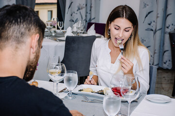 woman taking a bite from her meal while on a date with her partner