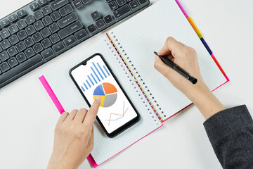 Woman holding smartphone with diagrams and charts on screen. Accountant checking annual financial reports on mobile. Woman doing home budget and checking monthly expenses
