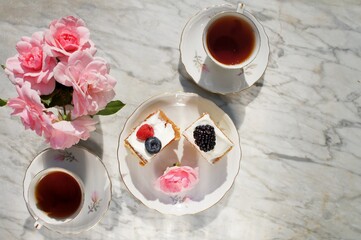 breakfast with black tea and berries cake on white marble table.