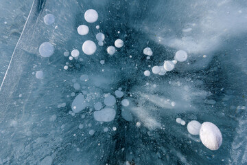 Beautiful ice of Lake Baikal with abstract cracks and frozen air bubbles