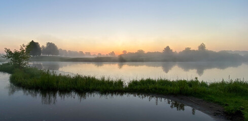 Obraz na płótnie Canvas early foggy sunrise on golf course pond leaves changing color