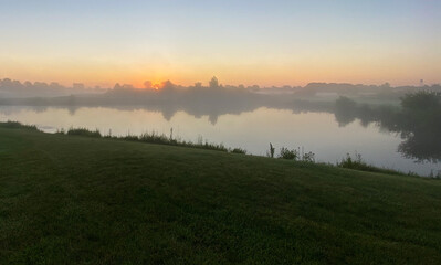 Naklejka na ściany i meble early foggy sunrise on golf course pond leaves changing color