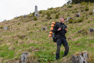 man in sportswear posing with a backpack on his shoulders in nature
