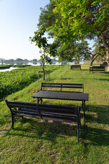 Tables and benches in green park with lake and sky