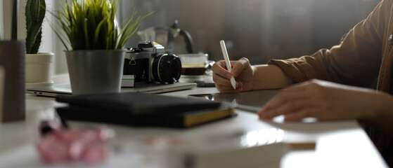 Female photographer working with mock up tablet on table with camera and supplies in studio