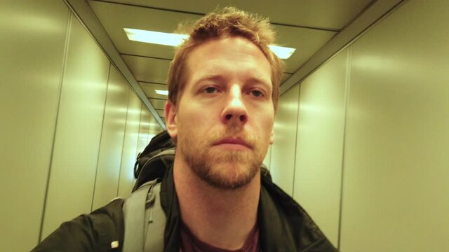 man selfie walking through tight airport corridor.