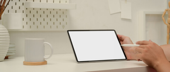 Male worker pointing on mock up tablet with stylus pen while sitting at worktable in home office