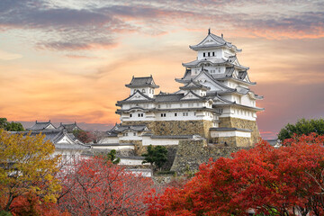 Himeji Castle and red maple leaves in evening sunlight and twilight sky in Himeji city, Hyogo...