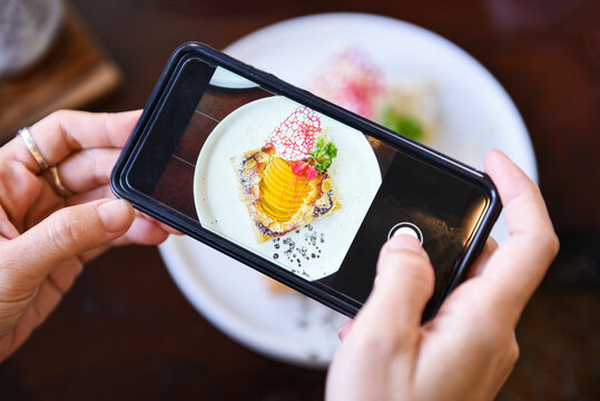 Food photography woman hands make photo cake with smartphone - taking photo food for post and share on social networks with camera smart phone in restaurant