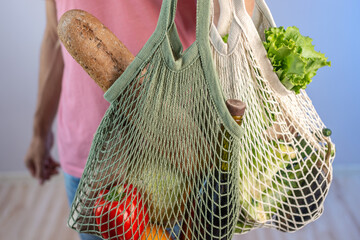 Modern young man is holding a string bags with purchases. Concept of eco-friendly behavior, the use of reusable bags and concern for the environment