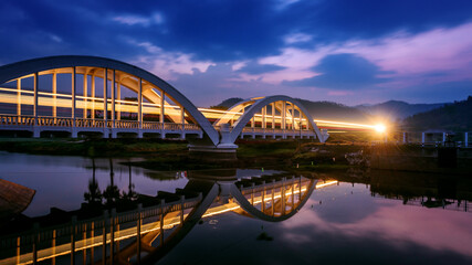 Long exposure Light from the train runs pass through bridge at dawn before sunrise , Tha Chom Phu...