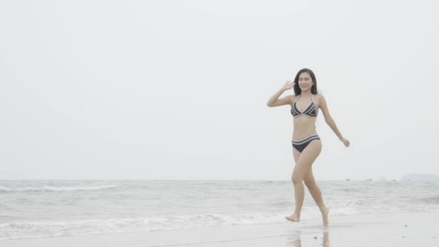 Beautiful tanned young asian woman in bikini walking at the beach, girl sexy happy and smiling on summer travel in vacation, woman relax wearing swimwear or swimsuit fashion running in tropical.