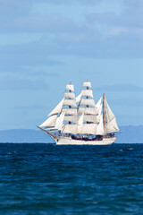 Obraz na płótnie Canvas Historic clipper sailing ship on open blue water in full sail.