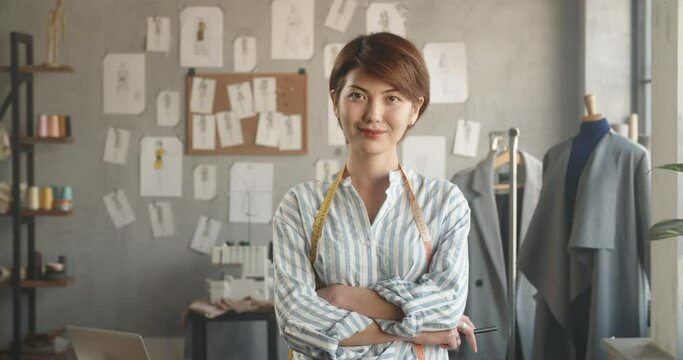 Authentic asian tailor working at her office, looking at camera and positively smiling - small business, people, success concept 4k footage portrait shot