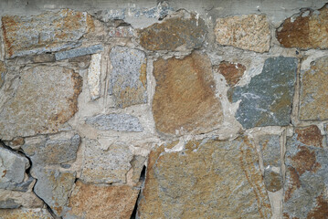 background of a solid stone wall made of cement, limestone and light rectangular bricks with an uneven surface of different colors and compositions