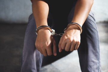 Arrest the offender. Prison male criminal standing in handcuffs with hands behind back. 