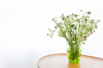 A bouquet of decorative flowers in a vase on table. Flowers in a vase by the window