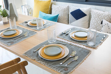table set on table with yellow plate setting in modern style dining room interior design concept.