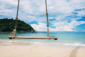 Wooden swing hanging on beach.