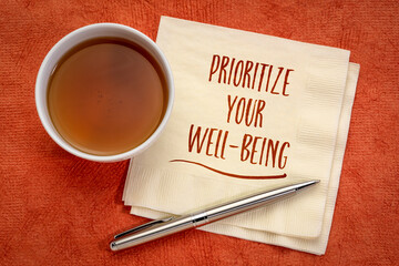 prioritize your well-being inspirational note - handwriting on a napkin with a cup of tea, healthcare, healthy lifestyle and personal development concept