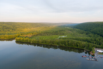 Late afternoon sun shines on Owasco Lake and Owasco Inlet near Moravia, Cayuga County, New York. A small marina is on the right. 