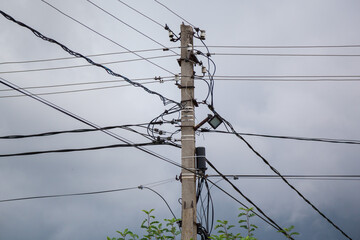 Close-up of power poles with wires on a blue sky with clouds.