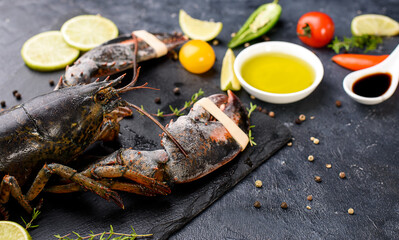 Delicious fresh lobster on dark background. Seafood with aromatic herbs, spices and vegetables - healthy food, diet or cooking concept