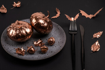 Festive Halloween table setting in a black style. Natural autumn golden painted leaves and pumpkins, flying  paper bats