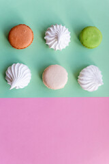 Colorful cake macaron or macaroon,white meringues on pink. turquoise pastel background. French almond cookies on dessert top view.French sweet cookie. Minimal food bakery concept. Dessert cake