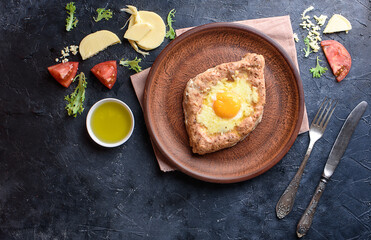 Fresh khachapuri with wholegrain flour, cottage cheese, egg, sulugini cheese, vegetables, butter, greens, plate, fork knife Delicious and healthy food