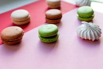Colorful cake macaron or macaroon,white meringues on red, pink background. French almond cookies on dessert side view.French sweet cookie. Minimal food bakery concept. Dessert cake