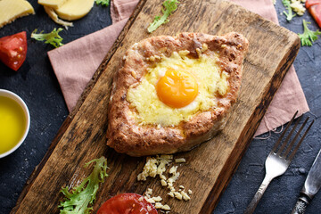 Fragrant khachapuri with cheese, egg, whole grain flour, cottage cheese on a wooded cottage. Proper food, and a delicious breakfast