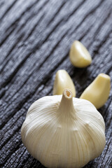 Fresh Garlic Bulb and Cloves on dark wooden background.